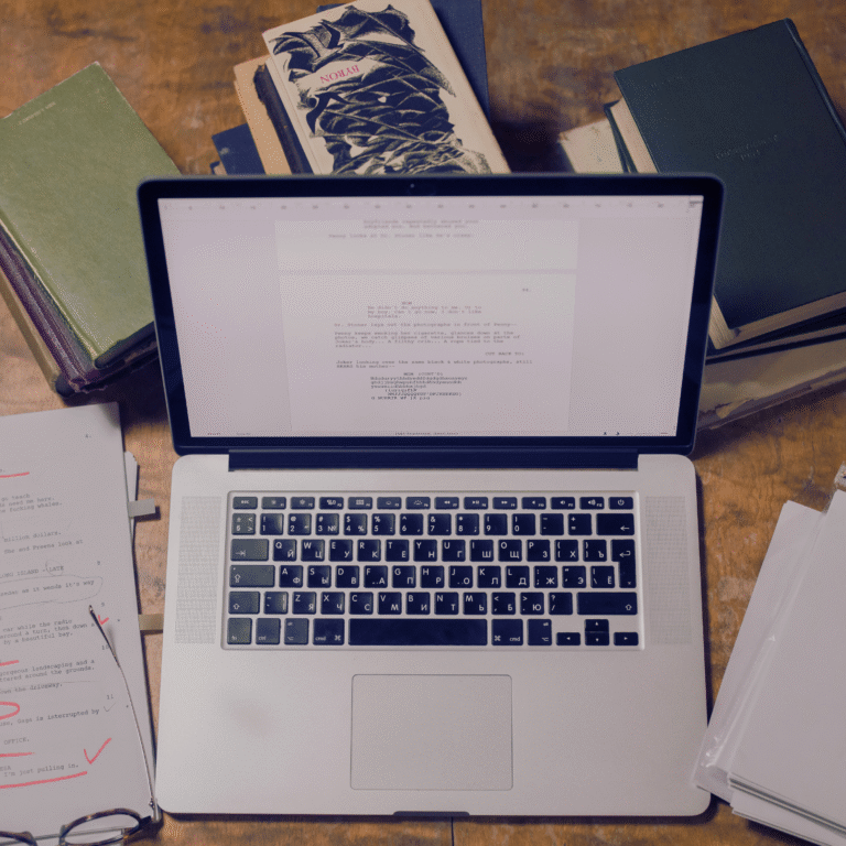 Computer and laptop with writing papers laying next to it